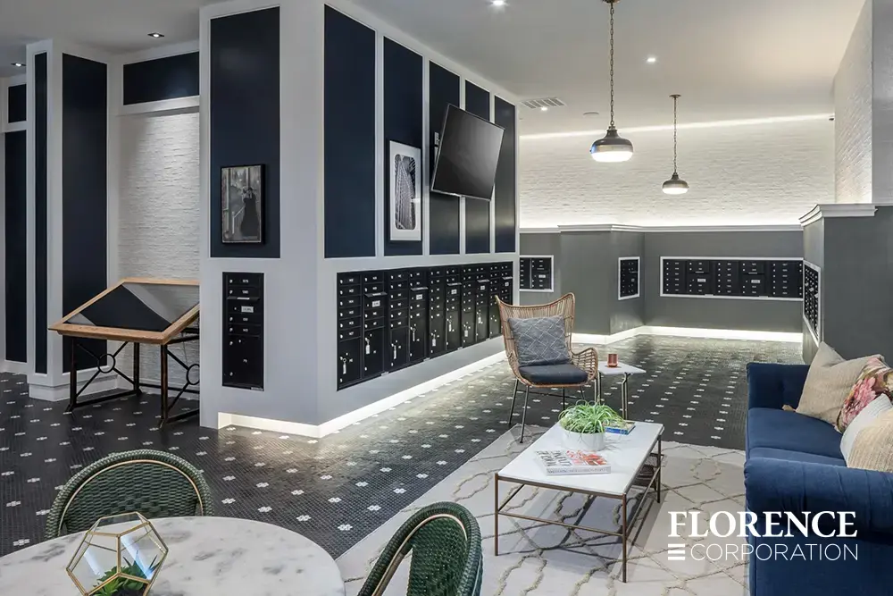 Recessed mount versatile™ 4C mailboxes in black installed in multifamily apartment building modern mailroom with sofas, chairs and tables