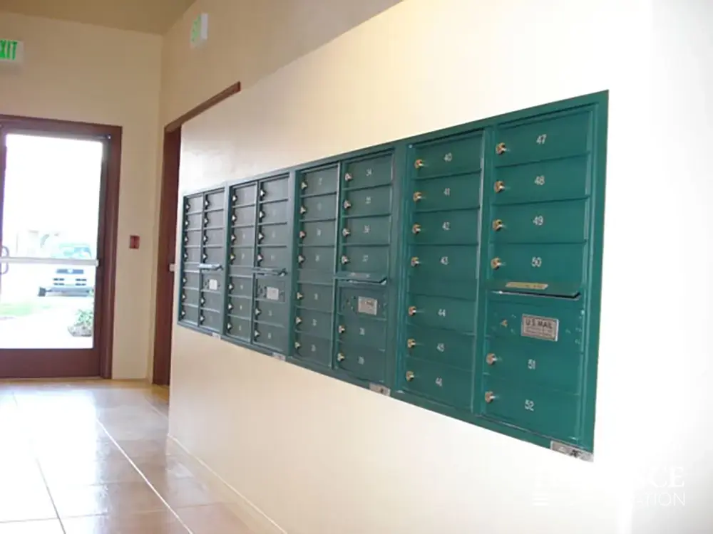 Recessed mount versatile™ 4C mailboxes in forest green installed in white wall in multifamily apartment building near resident entrance