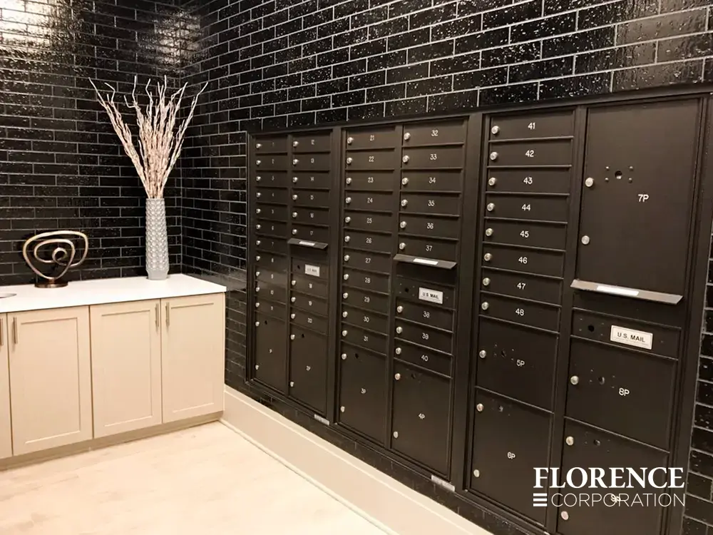 Recessed mount versatile™ 4C mailboxes in dark bronze installed in black tile wall in modern lobby area of multifamily apartment building