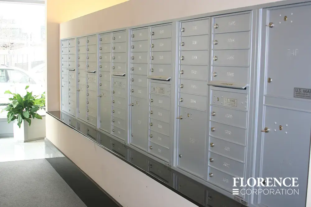 Recessed mount versatile™ 4C mailboxes in silver speck installed indoor of commercial building with green plant and black ledge