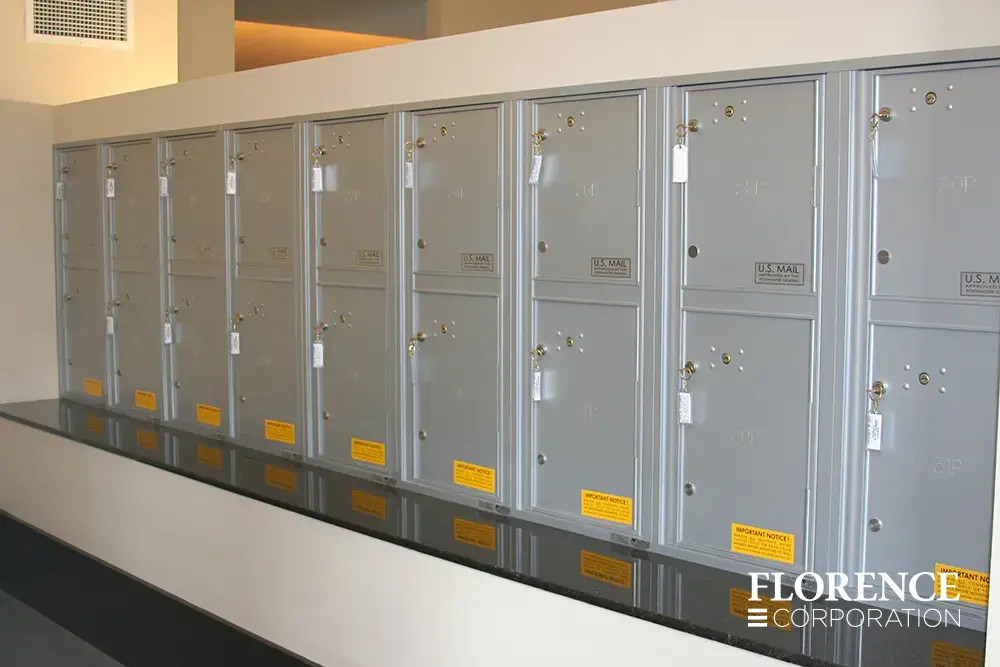Recessed mount versatile™ 4C parcel lockers in silver speck installed indoor on white wall with black stone ledge
