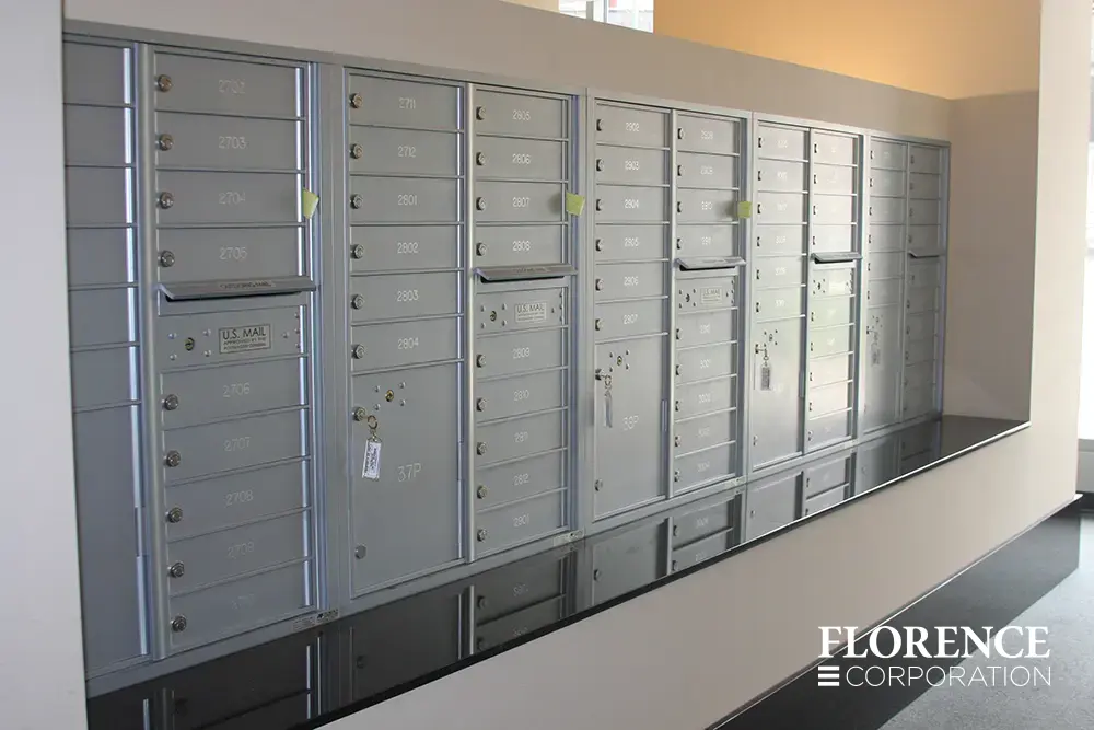 Recessed mount versatile™ 4C parcel lockers in silver speck installed indoor in cream wall in apartment building over black stone ledge