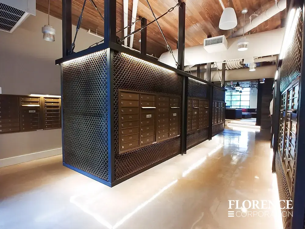Recessed mount versatile™ 4C mailboxes in dark bronze installed in suspended black metal fixture hanging from ceiling in modern mail room with architectural design touches