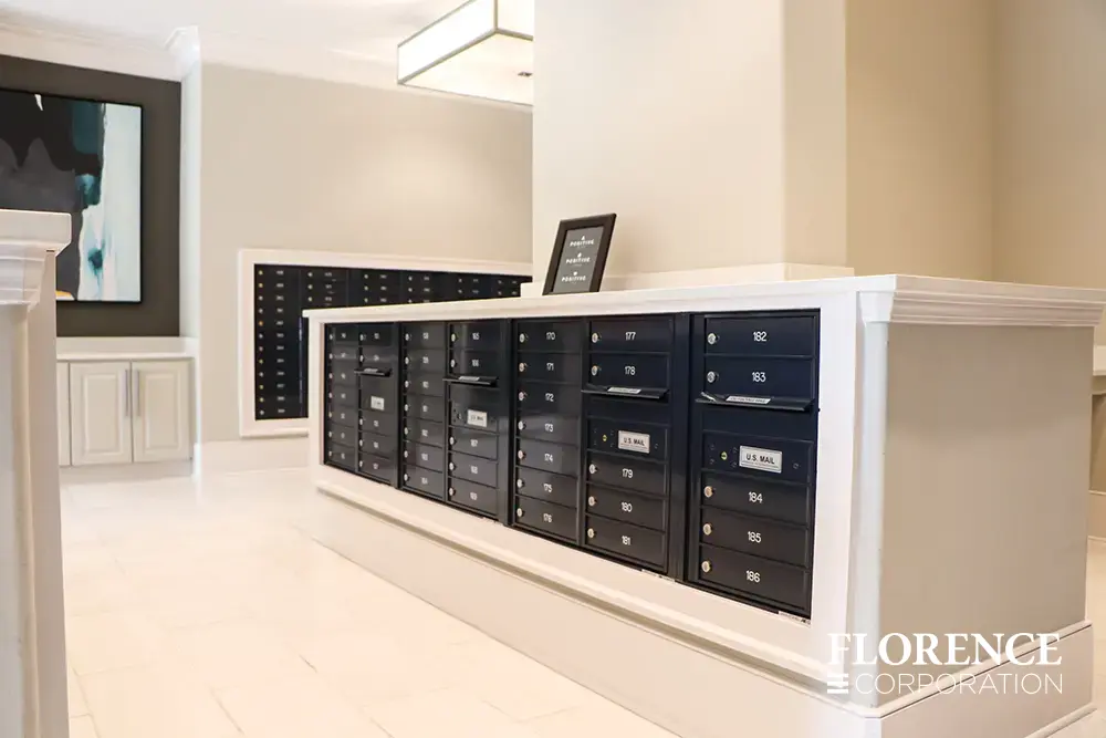 Recessed mount versatile™ 4C mailboxes in black installed in modern chic well lit mailroom in multifamily apartment building with white cream walls , ceilings and floors