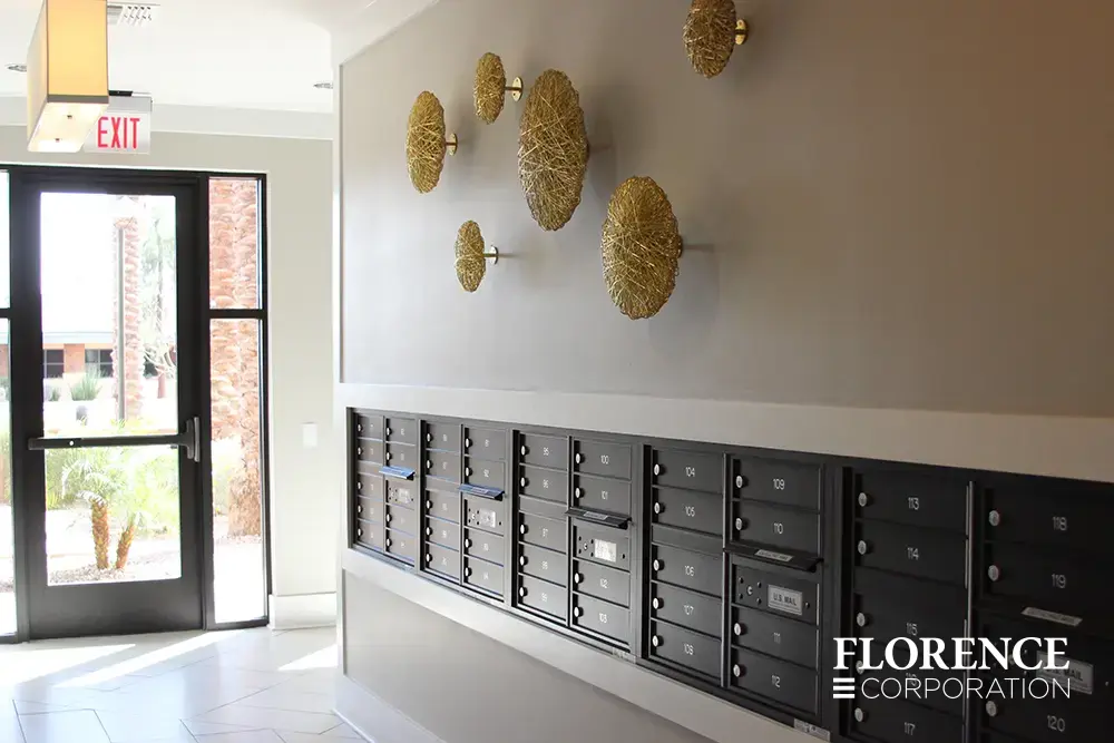 Recessed mount versatile™ 4C mailboxes in black installed in luxe apartment building with tile floor, wall art and bright exit door.
