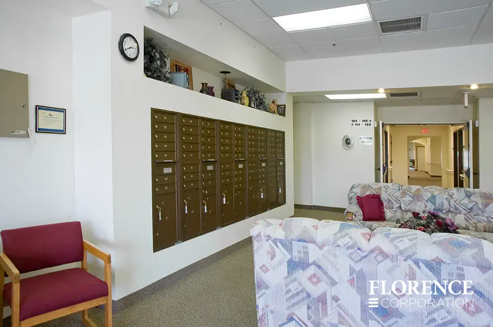 Recessed mount versatile™ 4C mailboxes in antique bronze installed in senior living home lobby area near couches and chairs