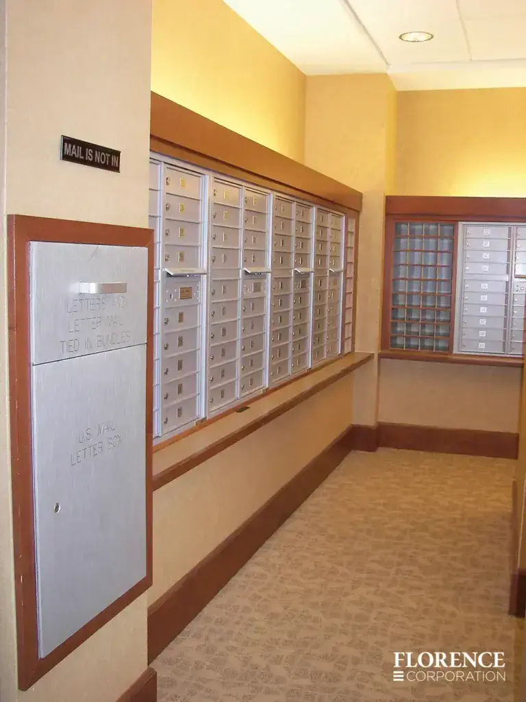 Recessed mount versatile™ 4C mailboxes and collection box accessory all in silver speck installed in multifamily apartment mailroom with wood trim and wallpaper