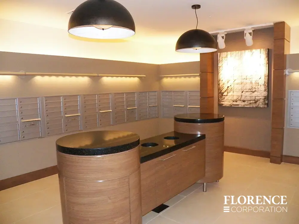 Recessed mount versatile™ 4C mailboxes in silver speck installed in multifamily apartment mailroom with wood and black recycling center in middle of room