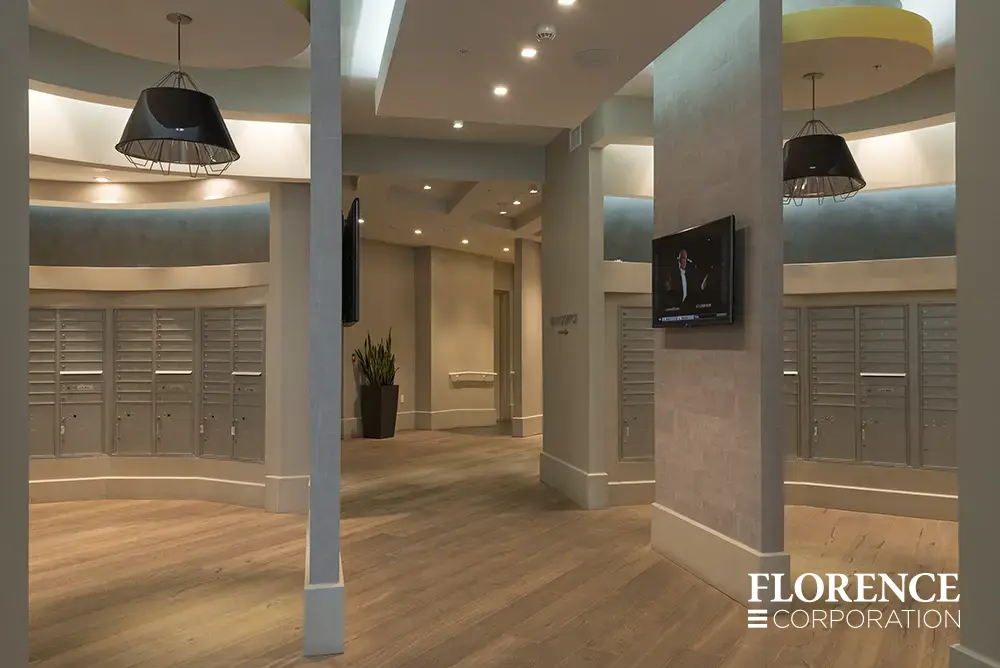 multiple curved rows of recessed mount versatile™ 4C mailboxes in silver speck installed in modern architectural mailroom with blue walls and plank flooring