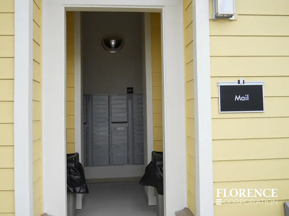 recessed mounted versatile™ 4C mailboxes in silver speck installed in open air mailroom in building with yellow siding