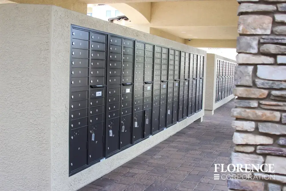 multiple rows of recessed mounted versatile™ 4C mailboxes in black mounted in cream stucco under covered open air mail center