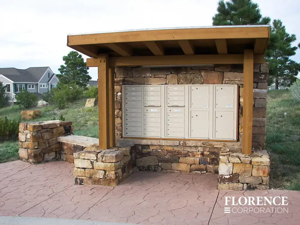 recessed mounted versatile™ 4C mailboxes in sandstone installed in custom-built wood and stone fixture outdoors in town home community