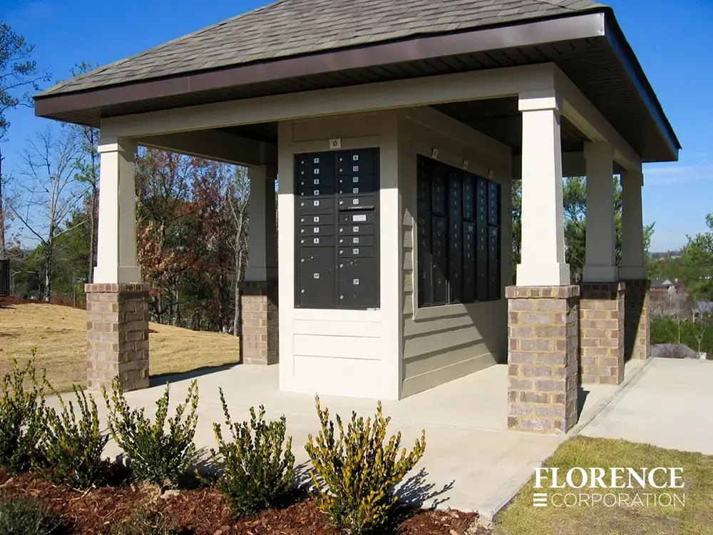 black recessed mounted versatile™ 4C mailboxes in cream wall under roof of shingled pavilion with brick and wood pillars