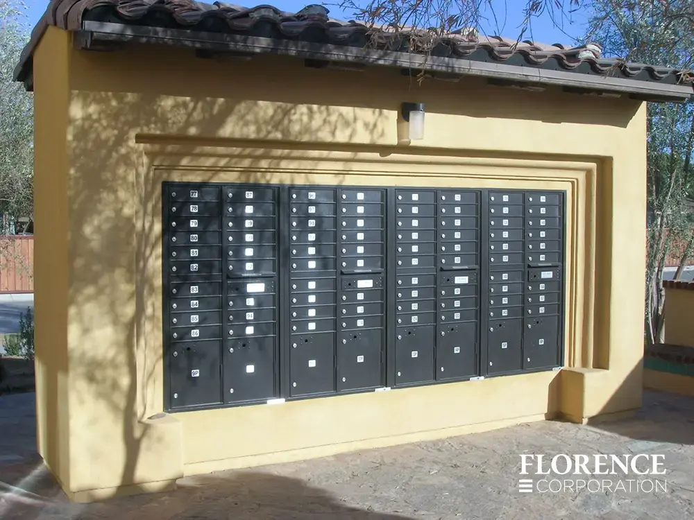 recessed mounted versatile™ 4C mailboxes in black installed in yellow concrete fixture in parking lot of multifamily residential area