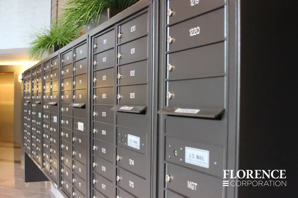 surface mounted versatile™ 4C mailboxes in dark bronze mounted indoor with decorative plants sitting on top of centralized mailboxes