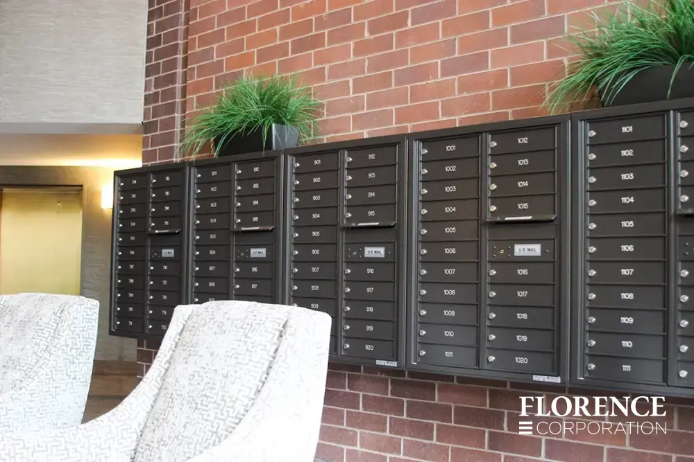 surface mounted versatile™ 4C mailboxes in dark bronze mounted on red brick wall with decorative green plants