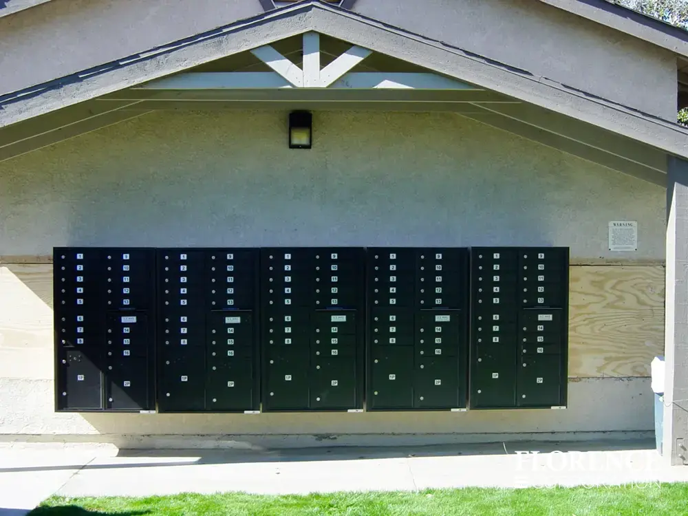 multiple surface mounted versatile™ 4C mailboxes in black mounted outdoor on side of community building