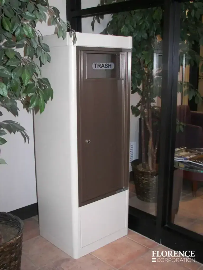 antique bronze versatile™ 4C waste bin installed in sandstone freestanding depot cabinet inside of commercial building lobby area
